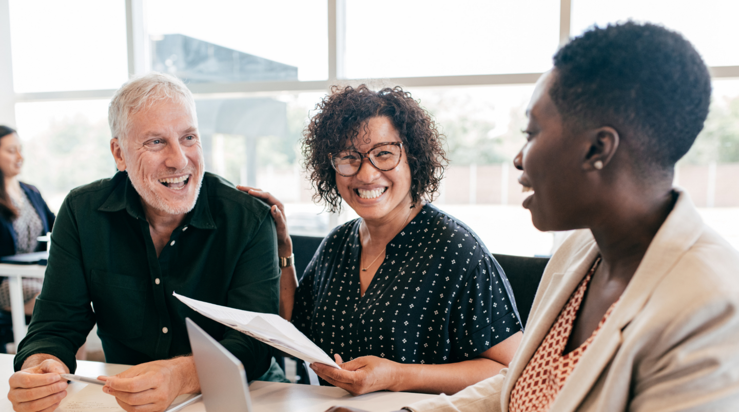 Drei Personen diskutieren lächelnd während eines Online-Seminars zu DE&I-Management