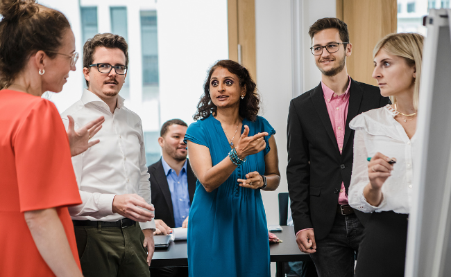 Diverse Gruppe diskutiert über DE&I in einem Meetingraum